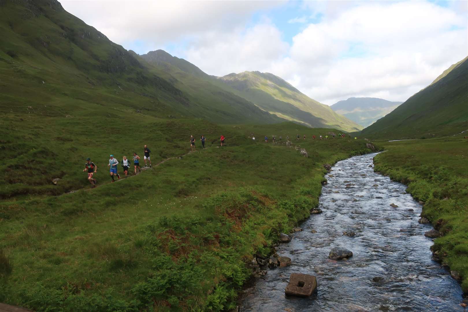 A stream of runners approaches the base of the climb.