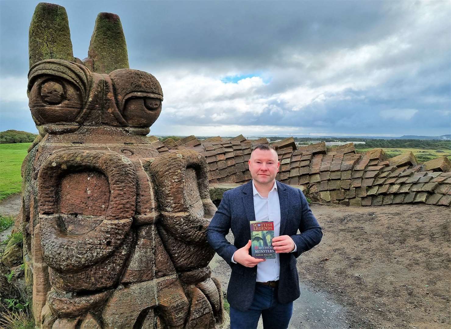 Aaron said he went on a hunt for the Loch Ness Monster. He is pictured here standing beside the Stone Dragon statue in Irvine.