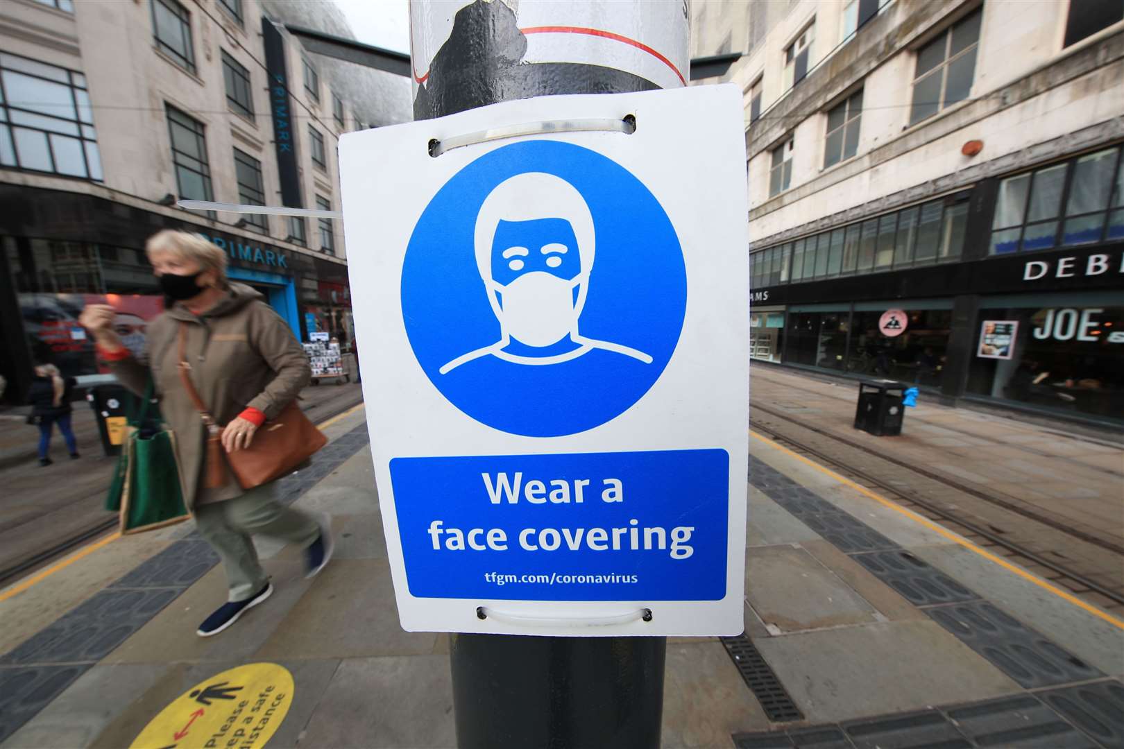 A sign advising on wearing face coverings at a tram stop in Manchester (Danny Lawson/PA)