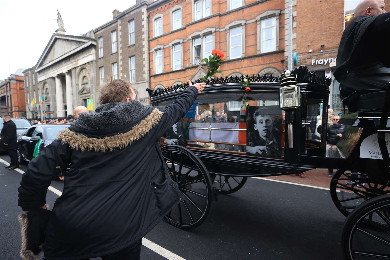 Flowers are thrown at the hearse as the funeral procession of Shane MacGowan makes its way through the streets of Dublin (Liam McBurney/PA)