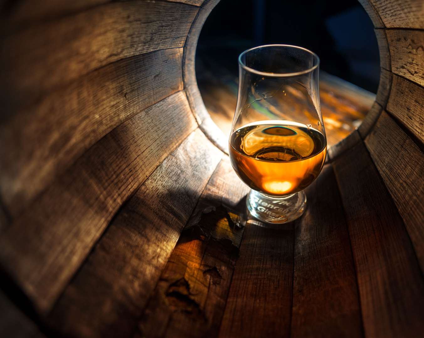 A glass of whisky in oak barrels.