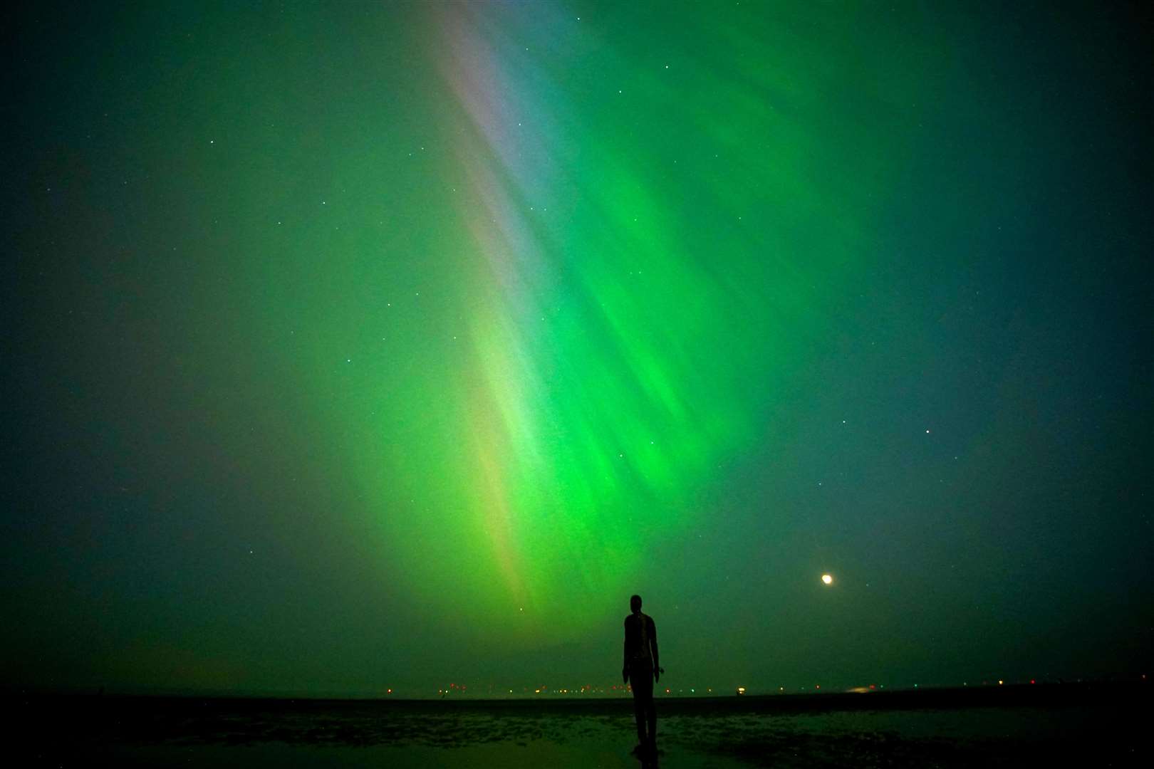 The aurora borealis, also known as the northern lights, glow on the horizon at Another Place by Anthony Gormley, Crosby Beach, Liverpool (Peter Byrne/PA)