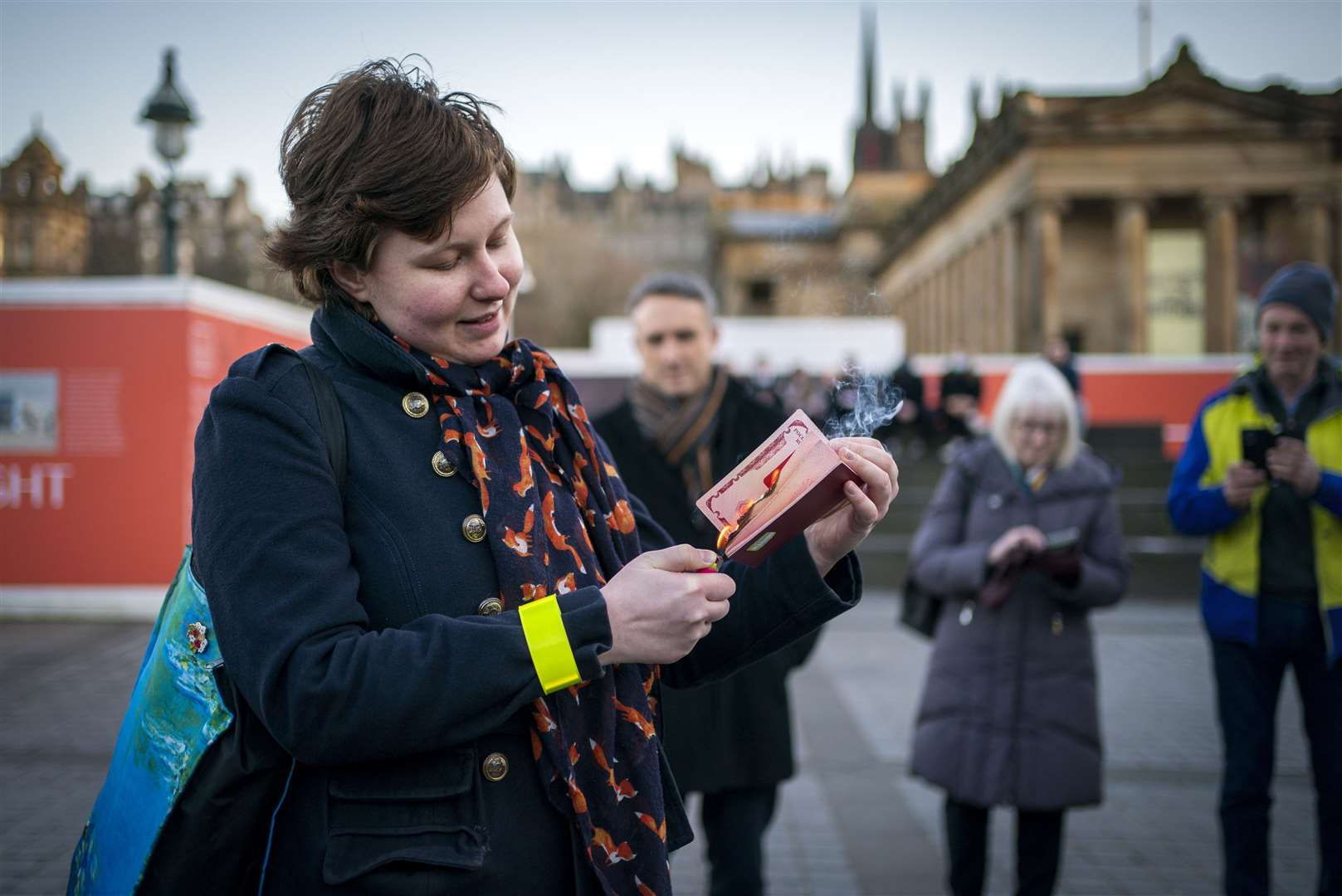 Anna Jakubova sets fire to her Russian passport with a lighter in the centre of Edinburgh to protest Putin’s invasion (Jane Barlow/PA)
