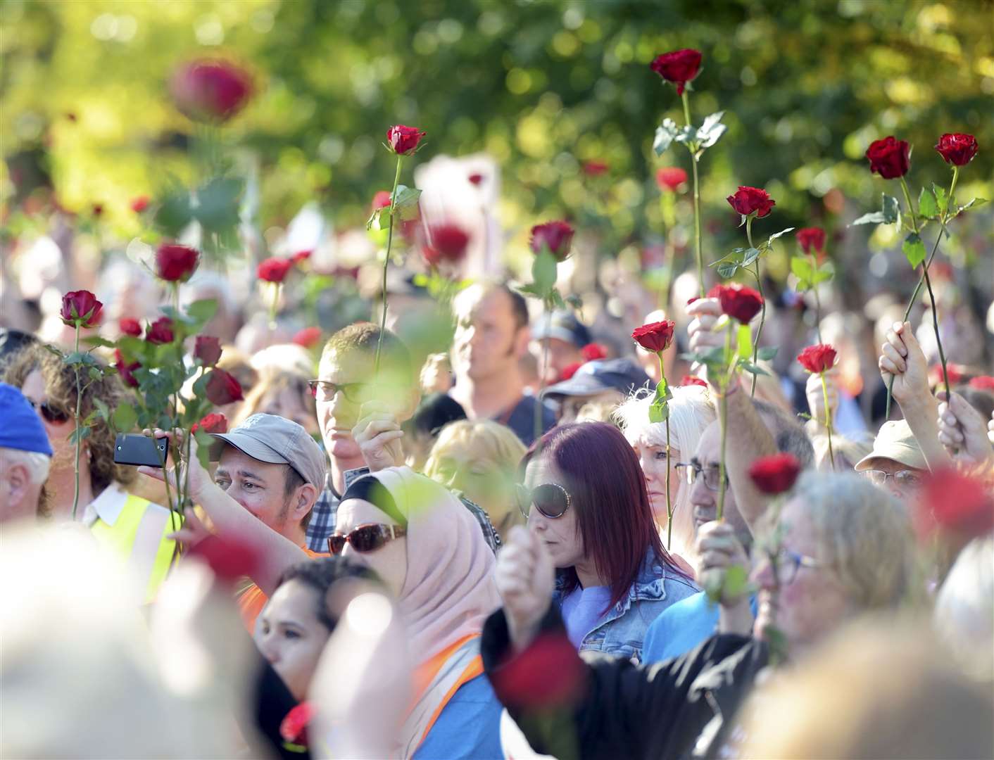 Before throwing their roses in the river the people gathered and held them in the air. Picture: James Mackenzie