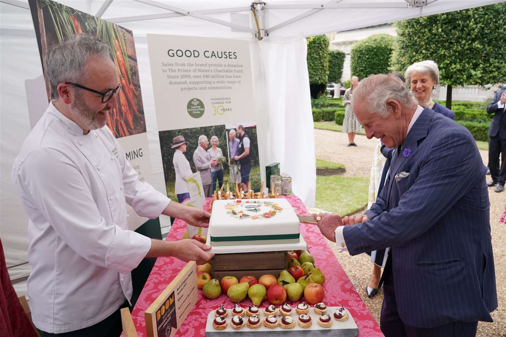 The King cuts a cake to celebrate four decades of the Prince of Wales’s Charitable Fund, with Waitrose senior chef Will Torrent, during a reception at Clarence House (Jonathan Brady/PA)