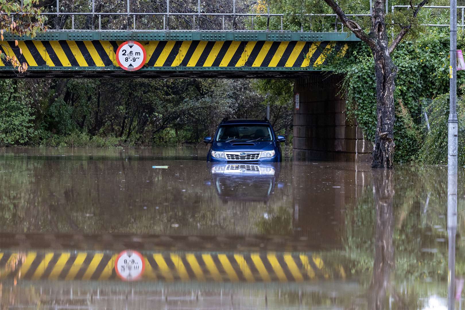 A car left abandoned under a flooded railway bridge in Dumbarton (Robert Perry/PA)