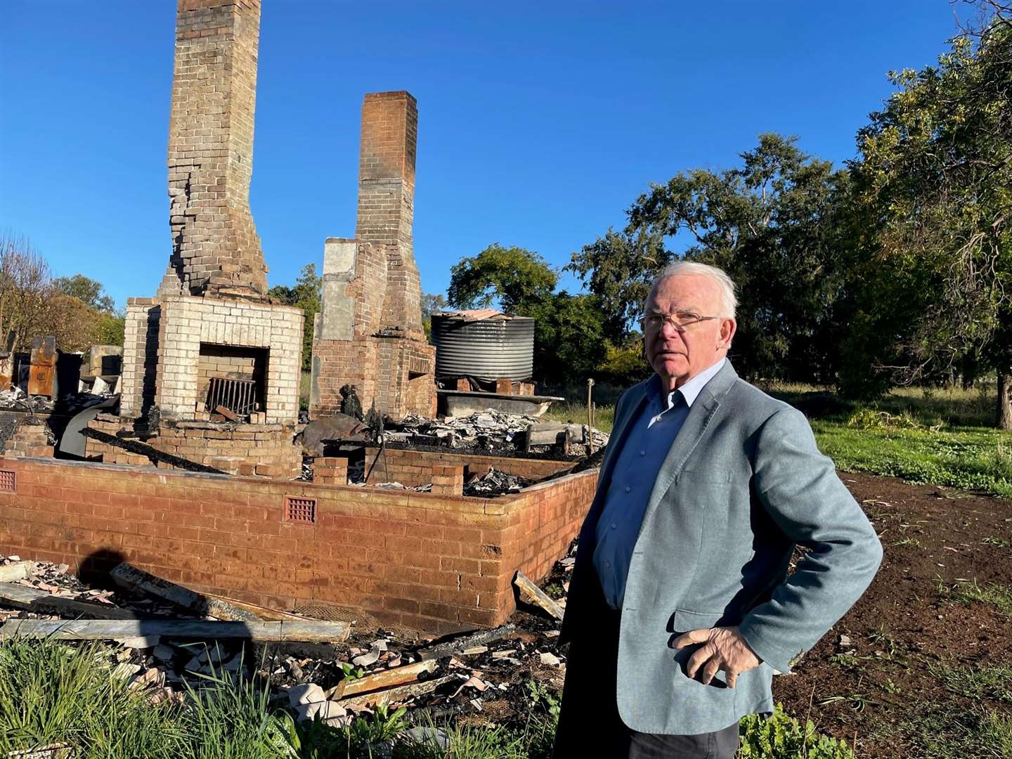 David Hill stands next to the burnt-out remains of one of the cottages British child migrants as young as five lived in at Fairbridge Farm School in Molong (Alana Calvert/PA)