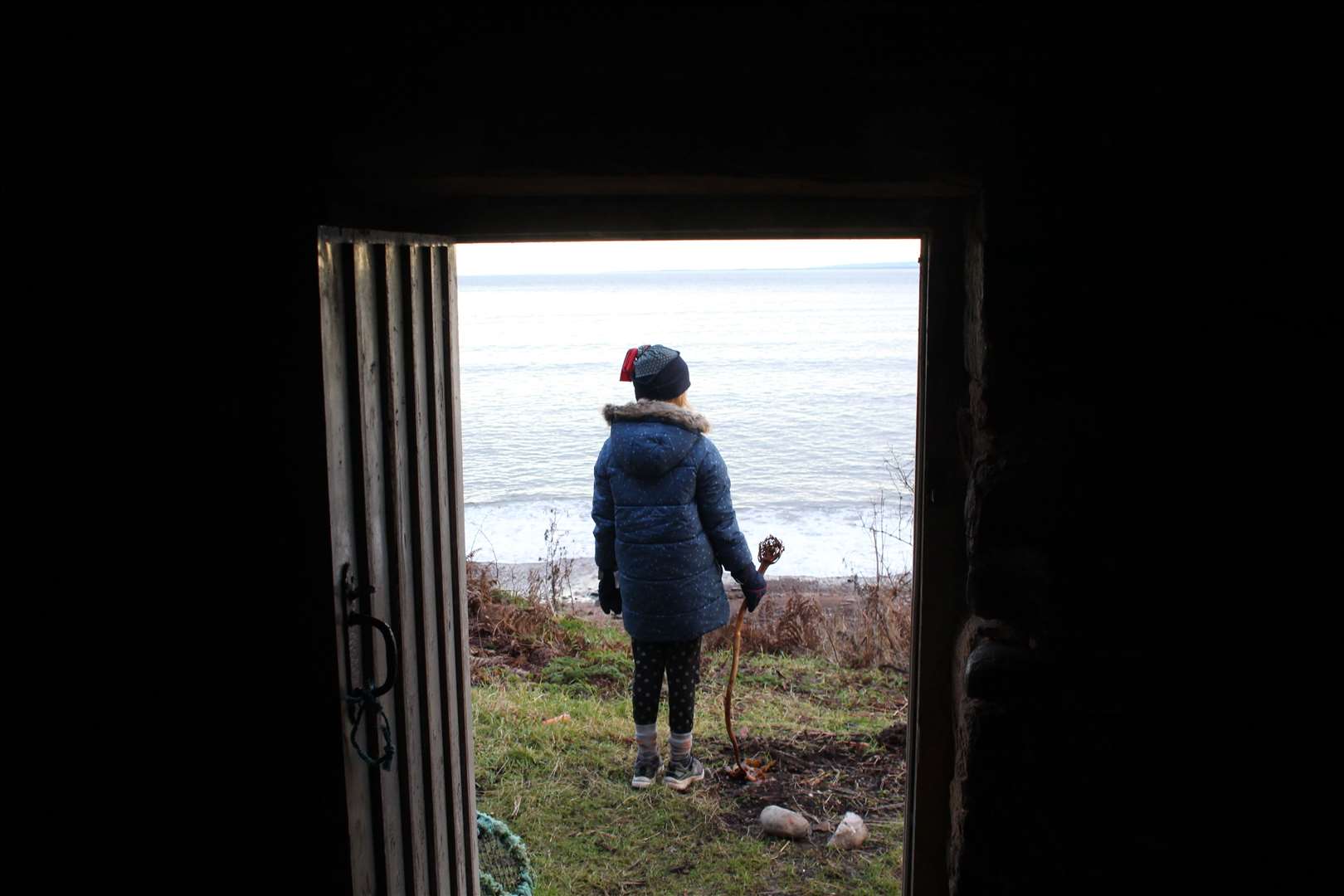 Jennifer looks out to sea, framed in the doorway of the salmon bothy.