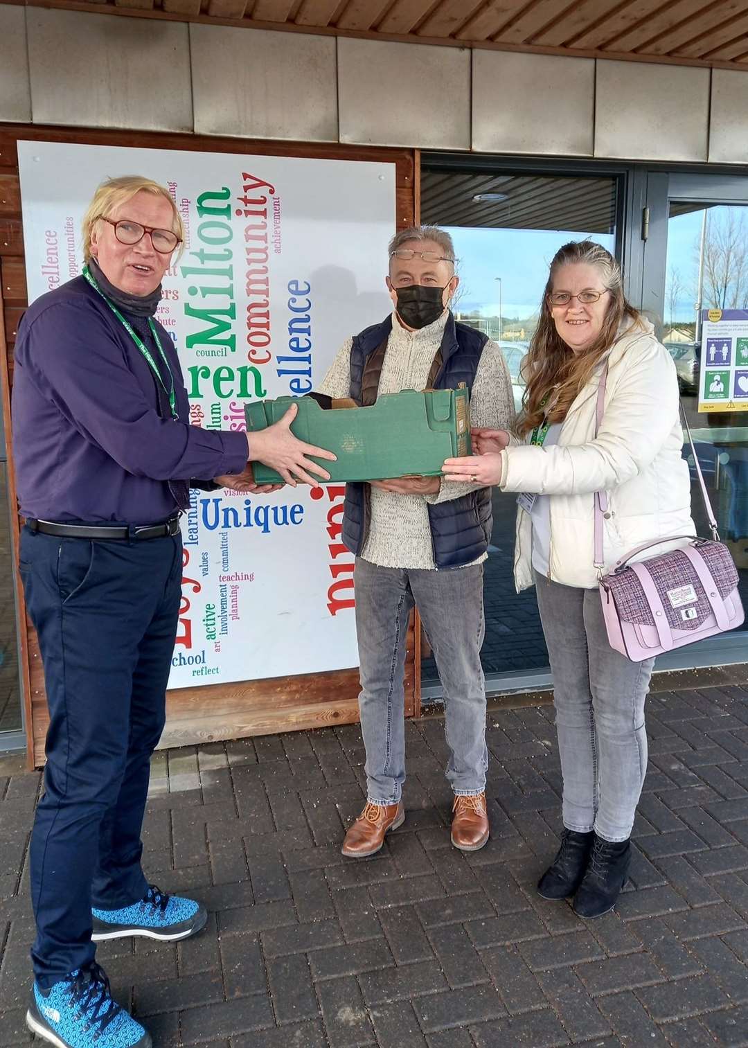 Dave and Liz from Budding Engineers handing a box of laptops to Robert Gill, headteacher of Milton of Leys Primary School in Inverness.