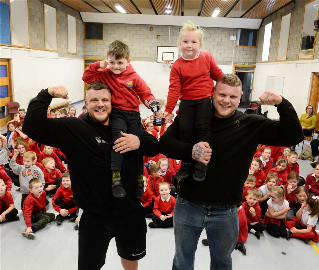 Tom and Luke Stoltman have been hailed an inspiration to Invergordon and the wider Highlands. The brothers are pictured here during a previous visit to South Lodge Primary for a talk to the pupils, giving then P1 pupils Leighton Williamson and Alise Goba a lift. Picture: Gary Anthony