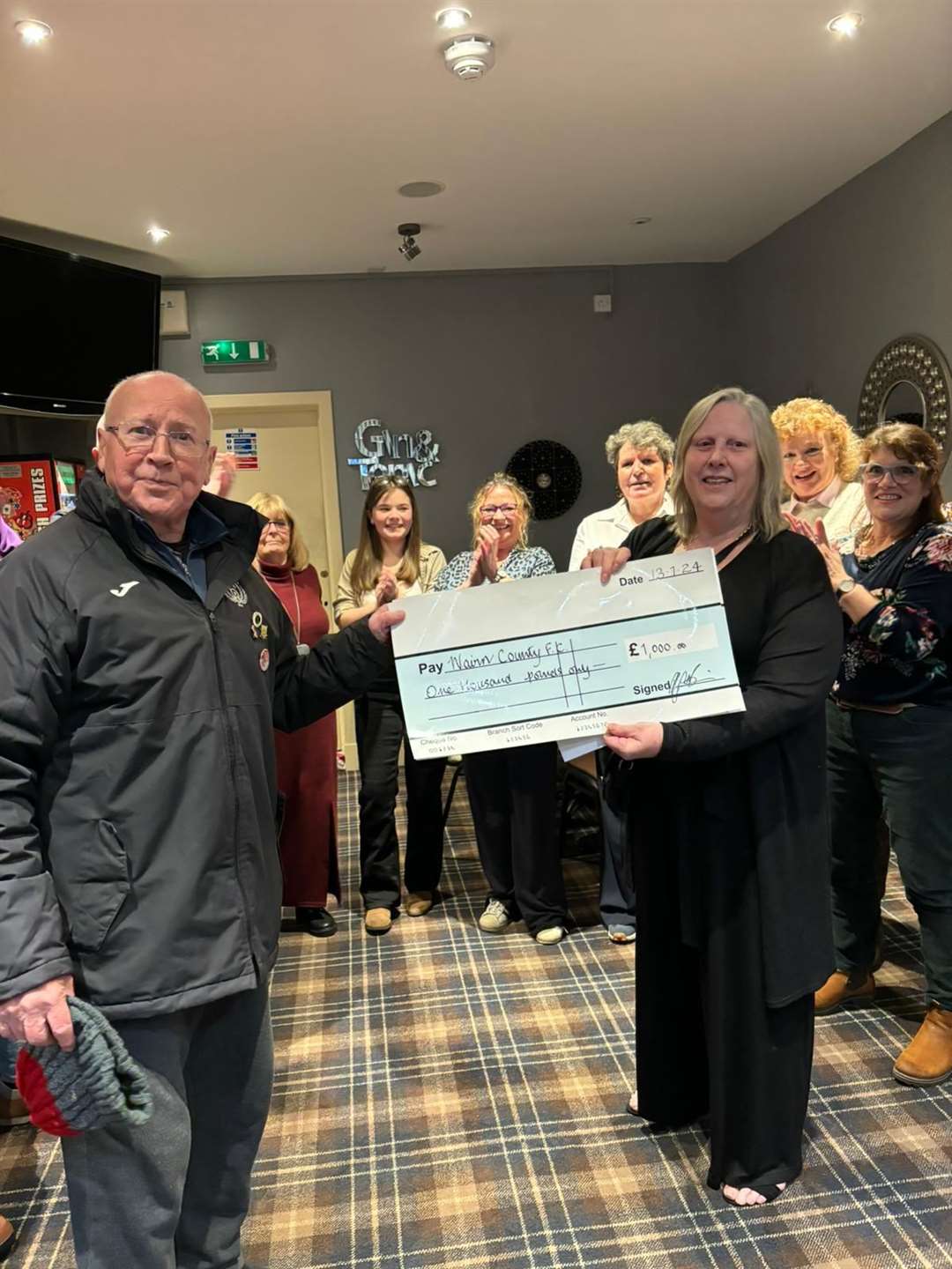 Alex 'Scoosh' Mackintosh from Nairn County receiving the cheque.