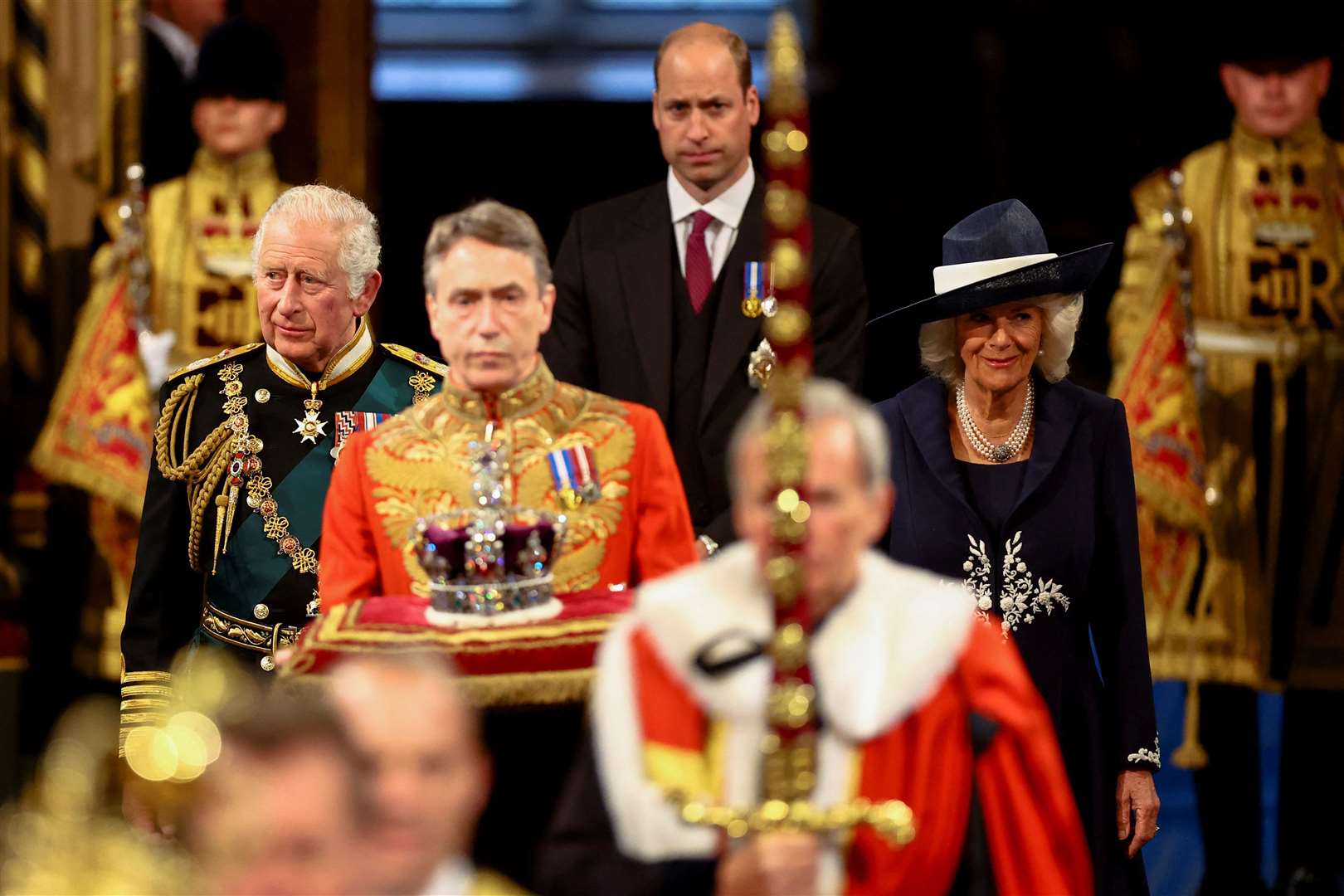 Charles and Camilla, followed by the Duke of Cambridge, proceed behind the Imperial State Crown through the Royal Gallery during the State Opening of Parliament in the House of Lords (Hannah McKay/PA)