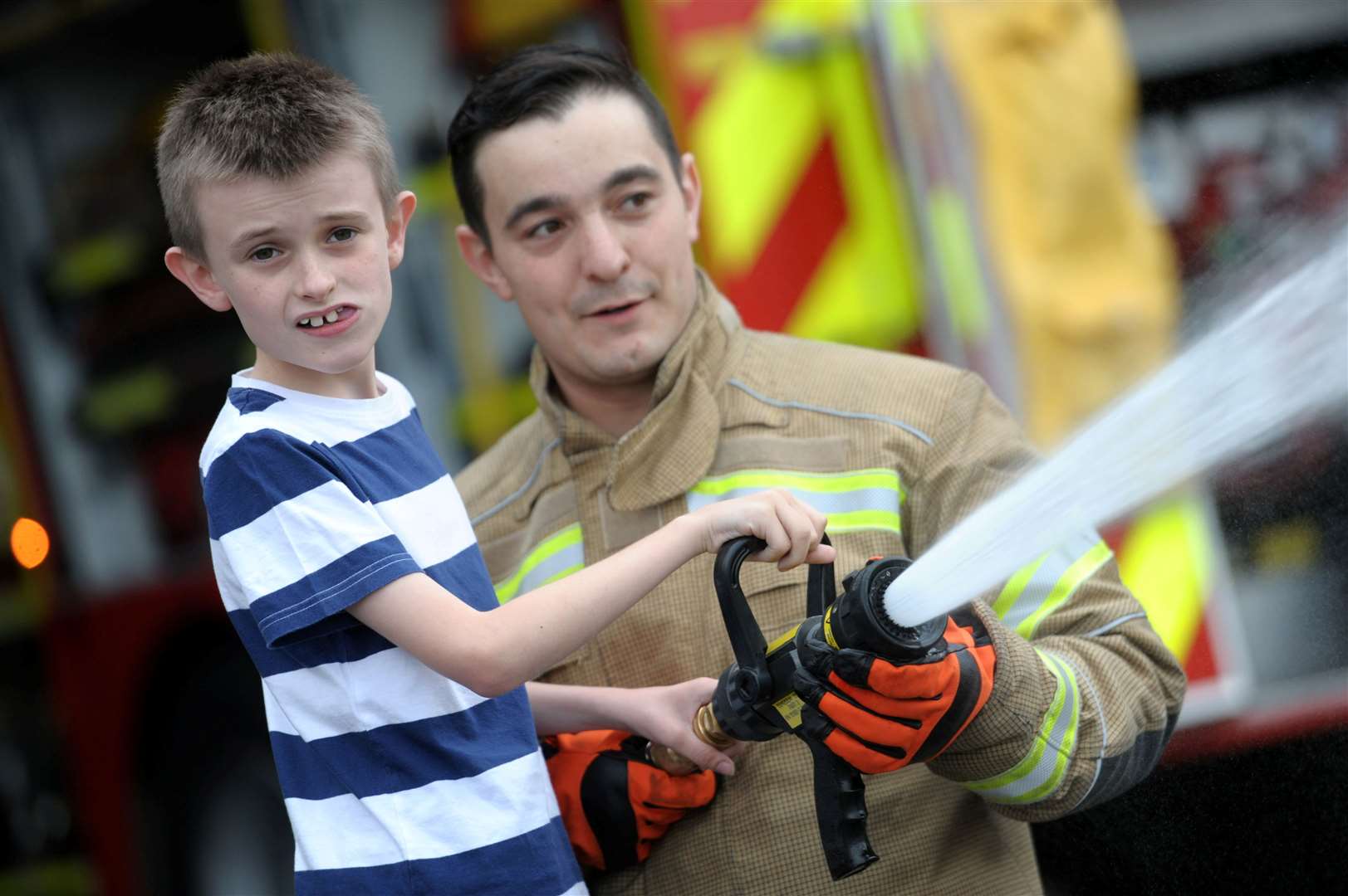 Fireman Dave Dugdale shows one of the children how to use the fire hose.