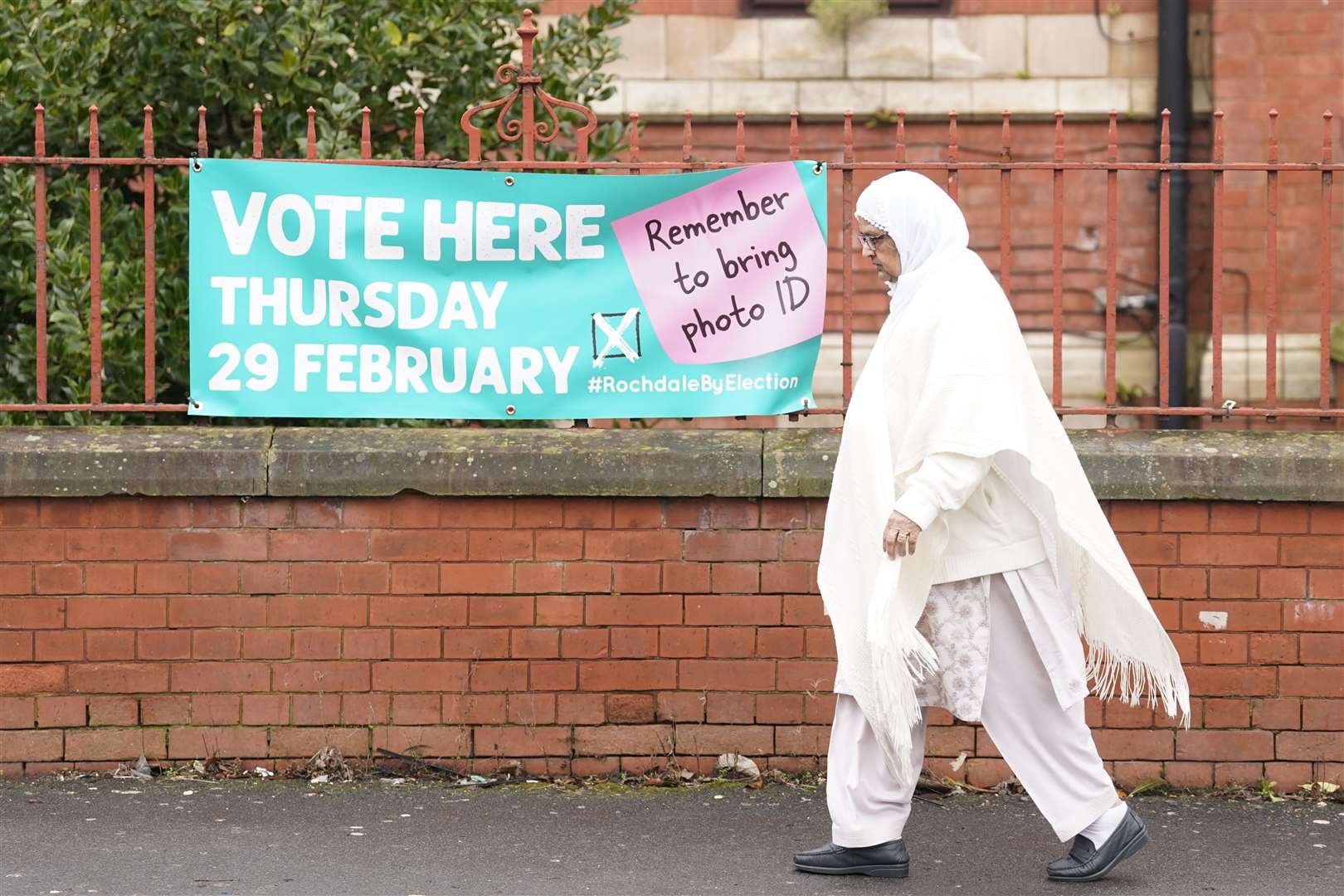 A woman walks past a sign for a polling station location in Rochdale, Greater Manchester, ahead of the by-election (Danny Lawson/PA)