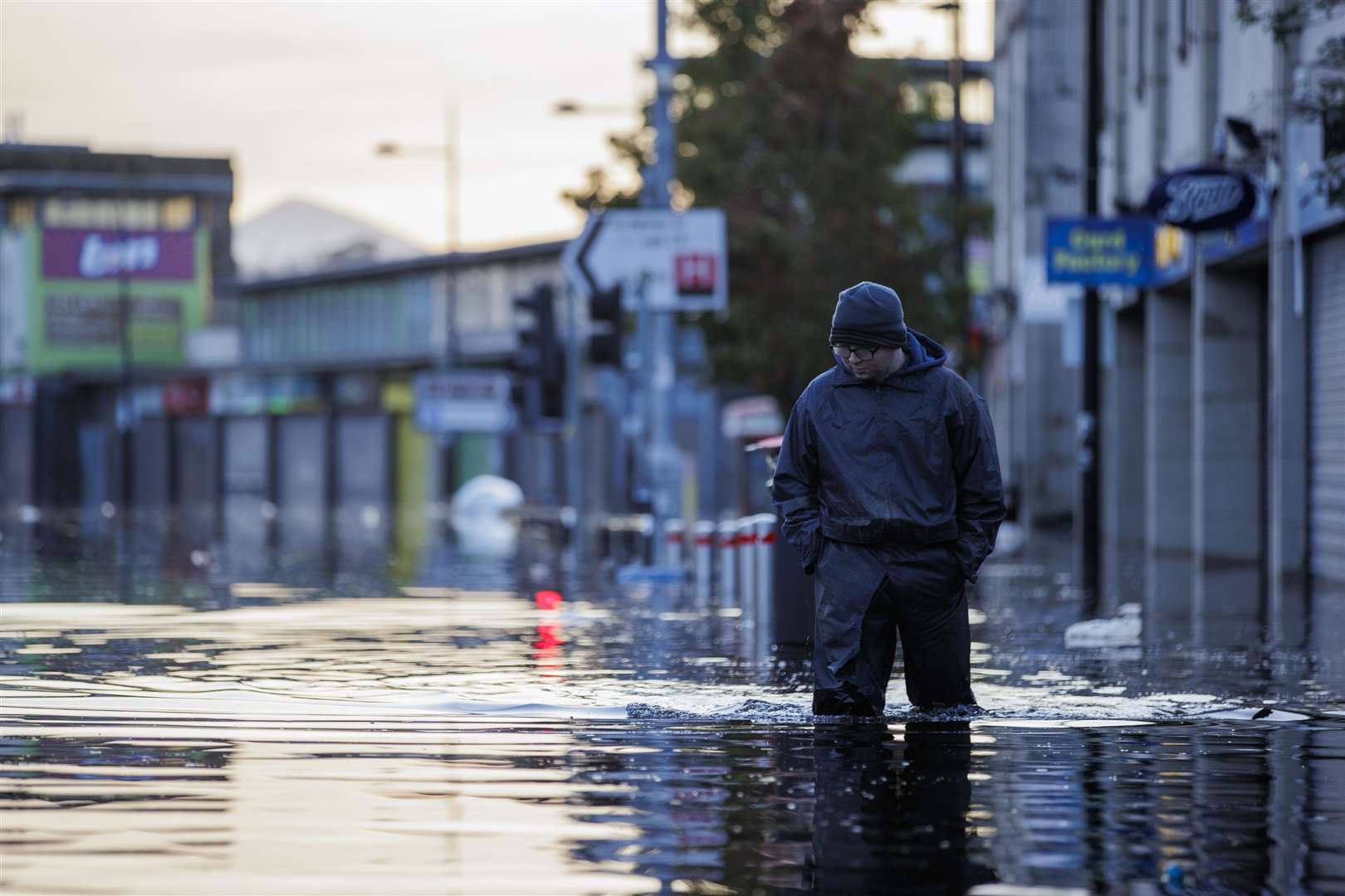 Michael McShane walks through floodwater on Market Street in Downpatrick, Northern Ireland (Liam McBurney/PA)