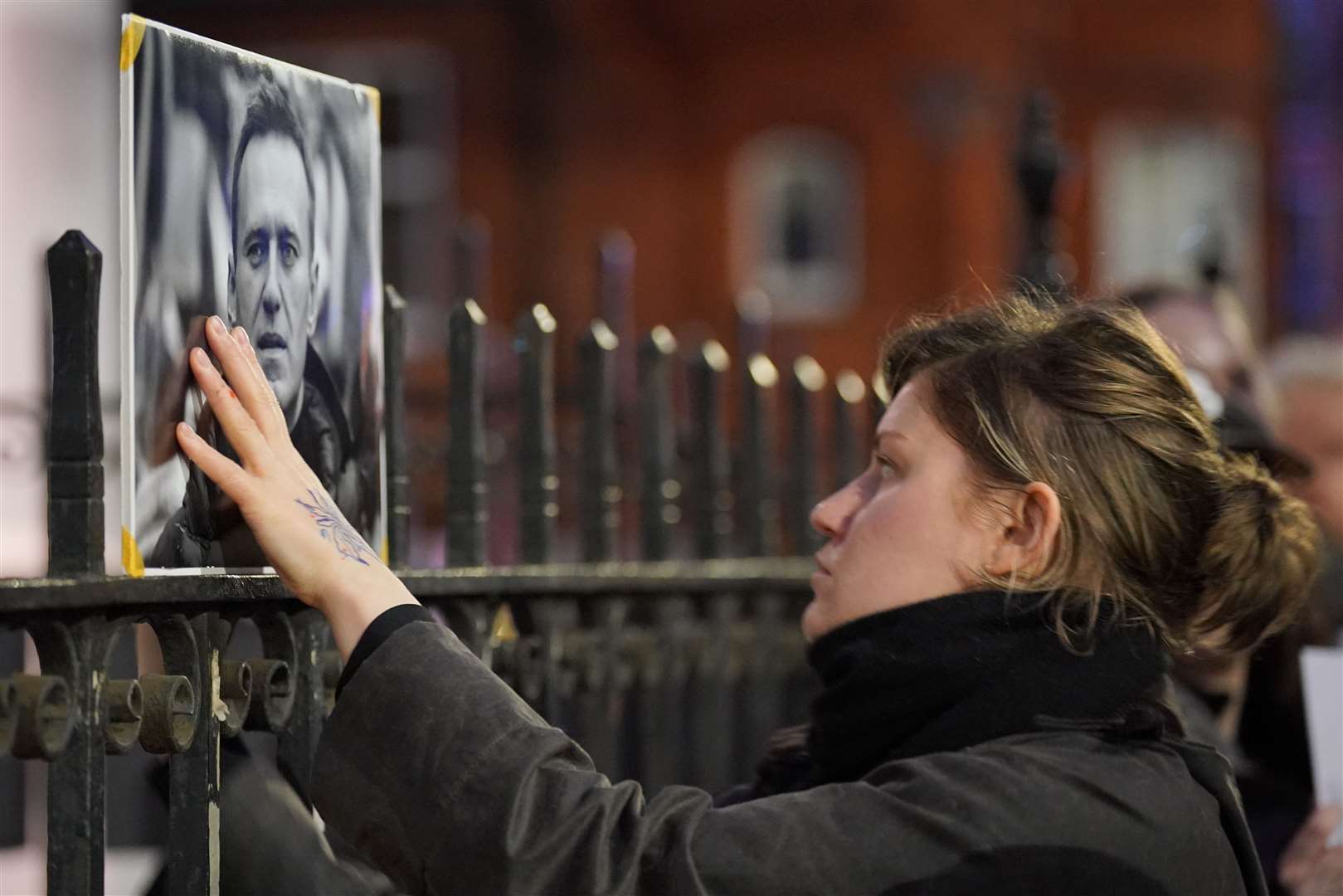 A women touches a picture of Alexei Navalny at a protest opposite the Russian Embassy in London (Jonathan Brady/PA)