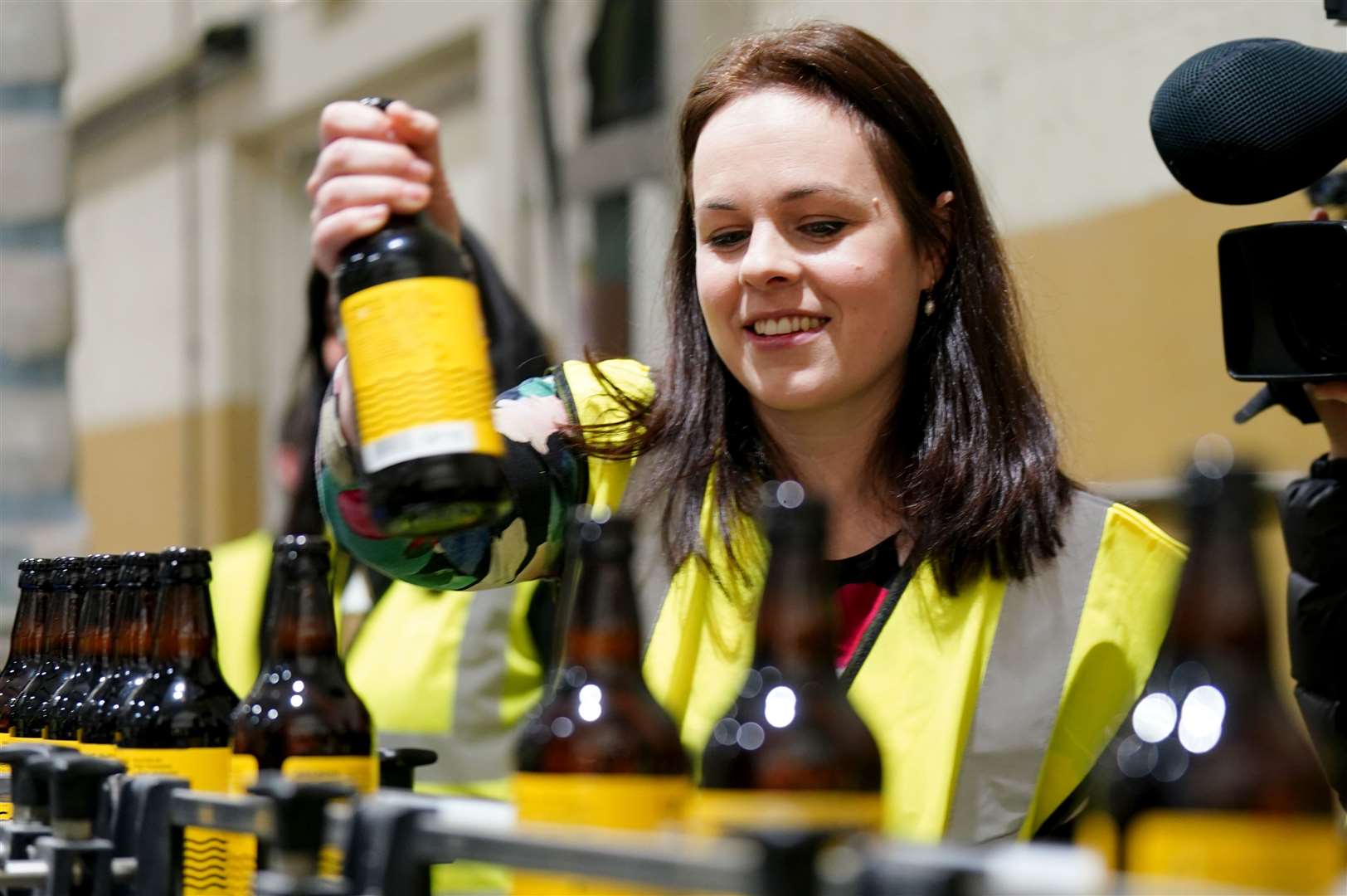 Kate Forbes has a go on the production line at the Cairngorm Brewery in Aviemore (Jane Barlow/PA)