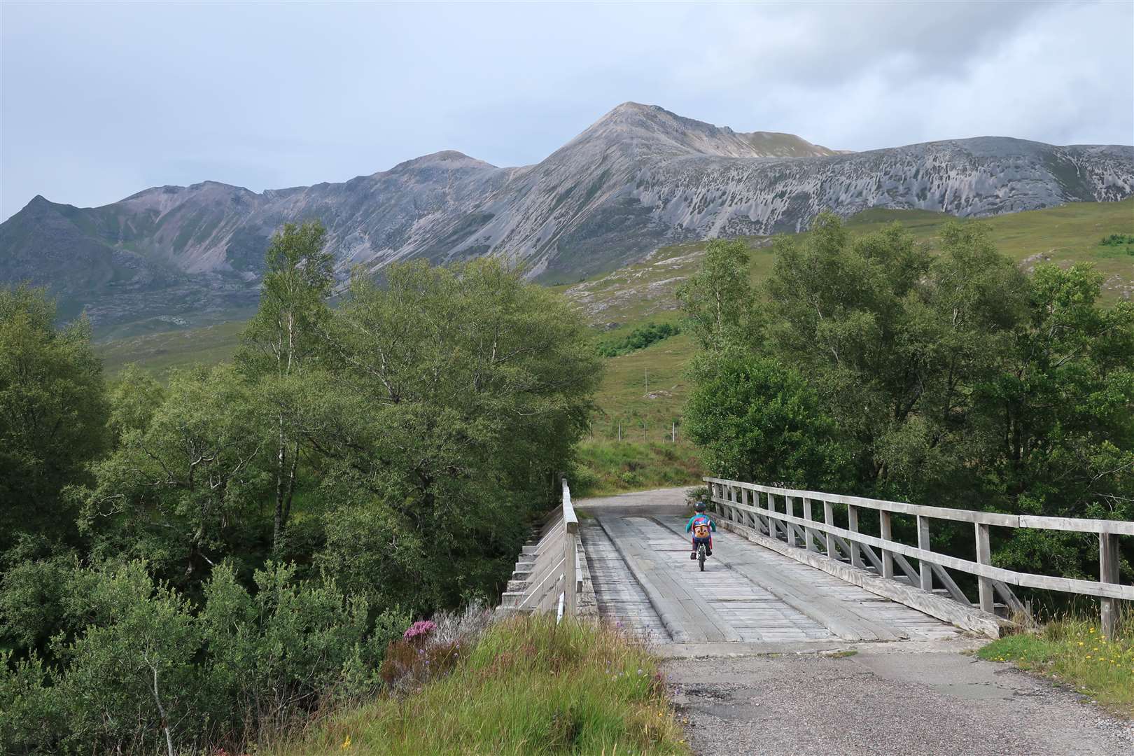 Matthew crosses the final bridge over the A'Ghairbhe with Beinn Eighe rising above.