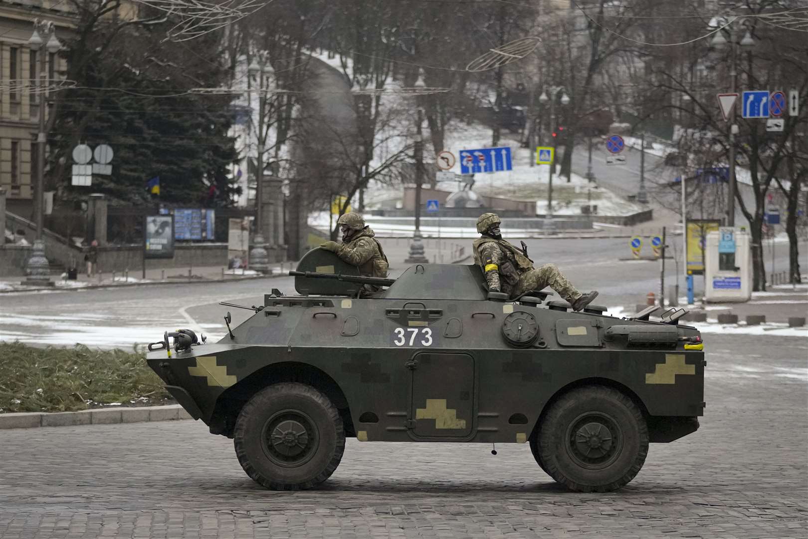 Ukrainian servicemen ride on top of an armored personnel carrier speeding down a deserted boulevard during an air raid alarm in Kyiv (Vadim Ghirda/AP)