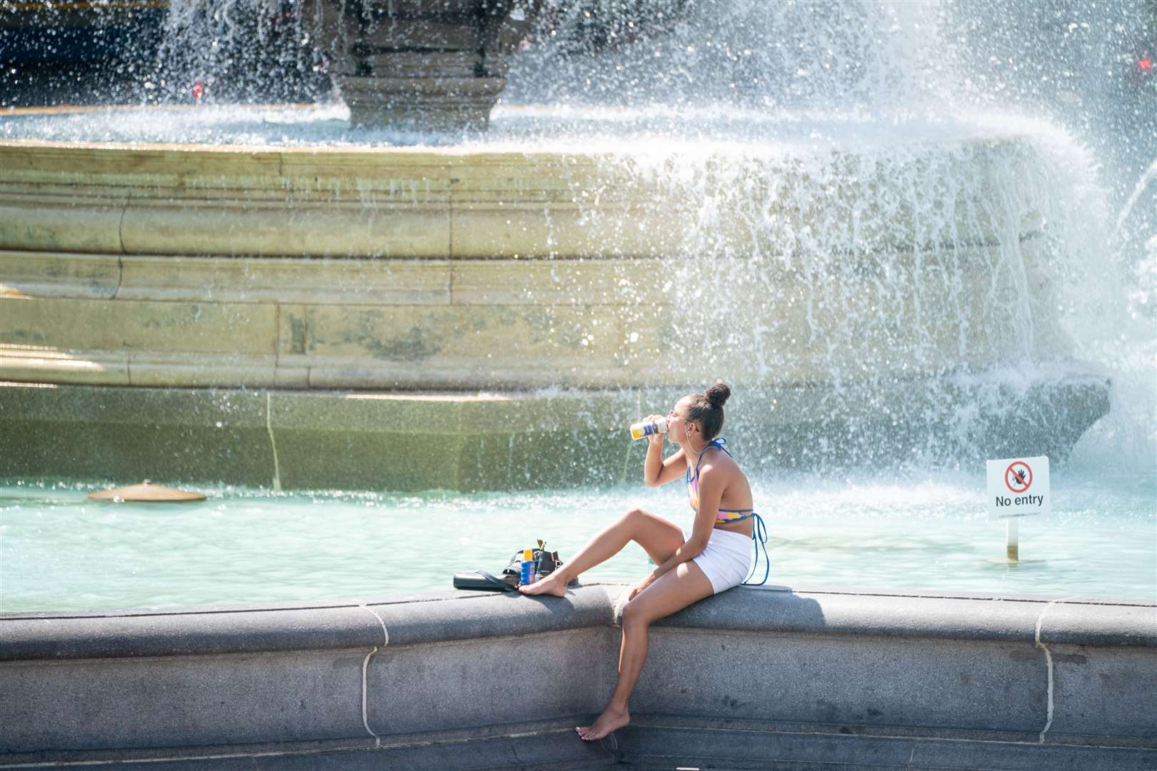 A woman sits by the fountains in Trafalgar Square, central London (Dominic Lipinski/PA)