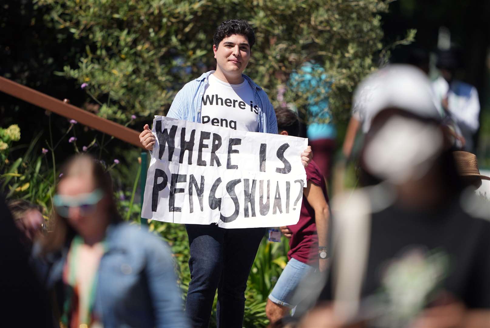 A protester holding a sign and wearing a T-shirt reading ‘where is Peng Shuai’ (PA)