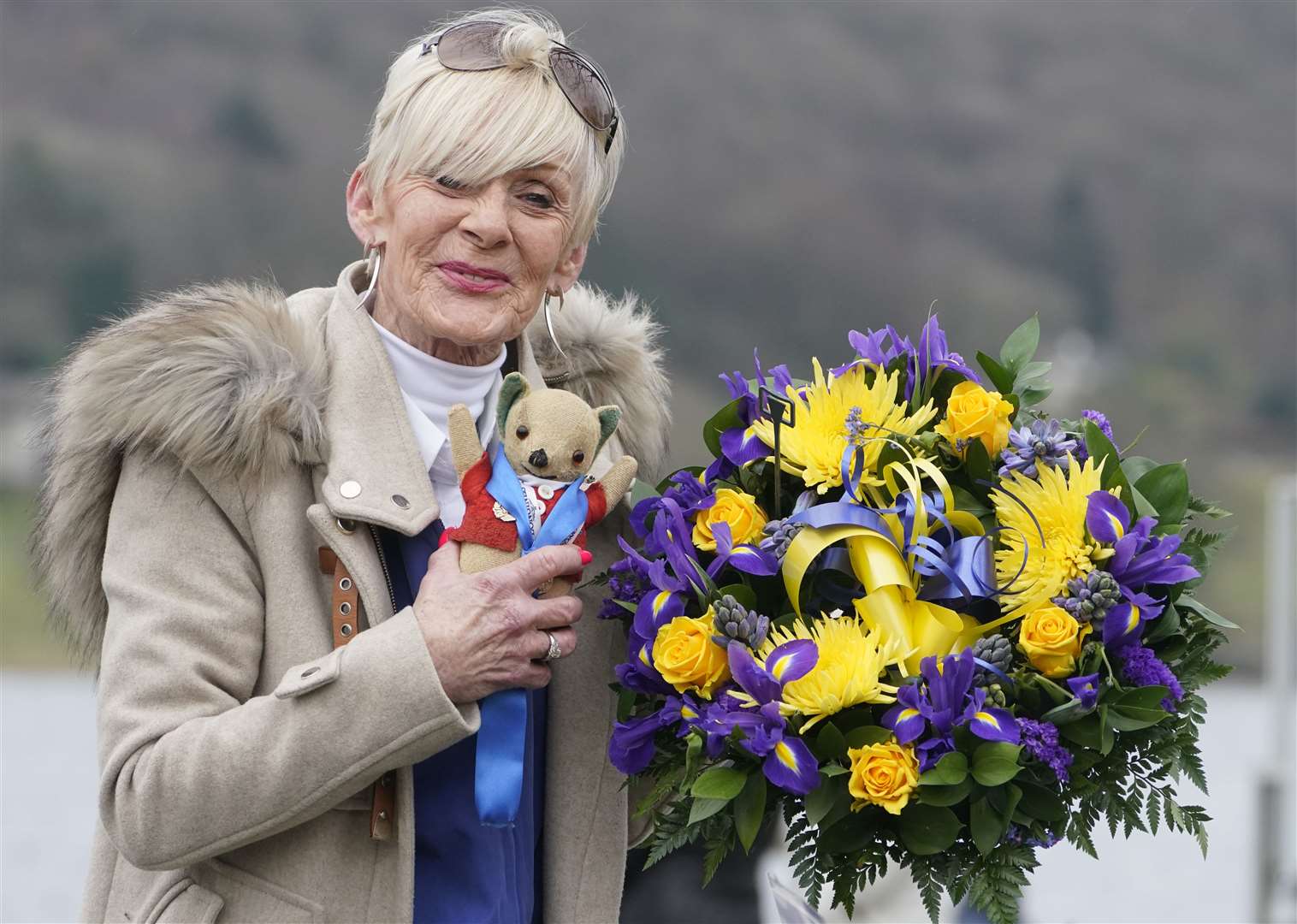 Gina Campbell, the daughter of Donald Campbell, holds a bunch of flowers at Coniston Water in 2021 to mark the 100th anniversary of his birth (Owen Humphreys/PA)