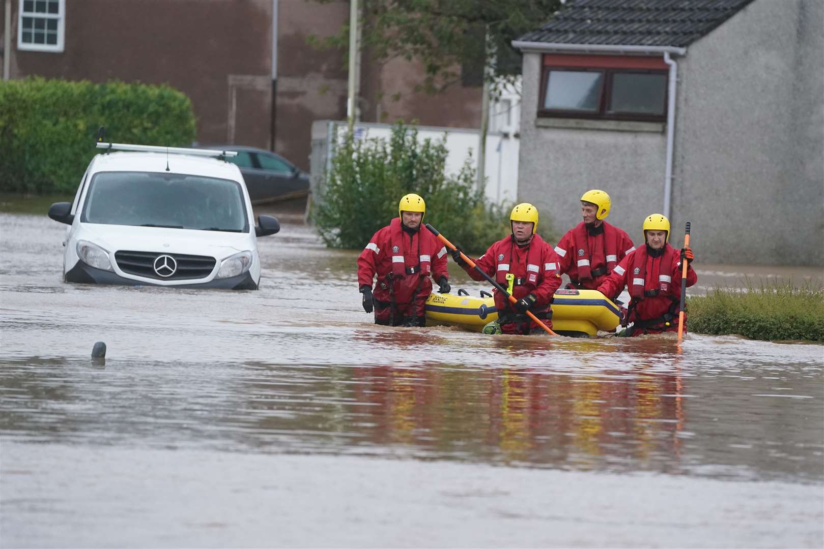 Members of a Coastguard rescue team wade through floodwaters in Brechin (Andrew Millgan/PA)