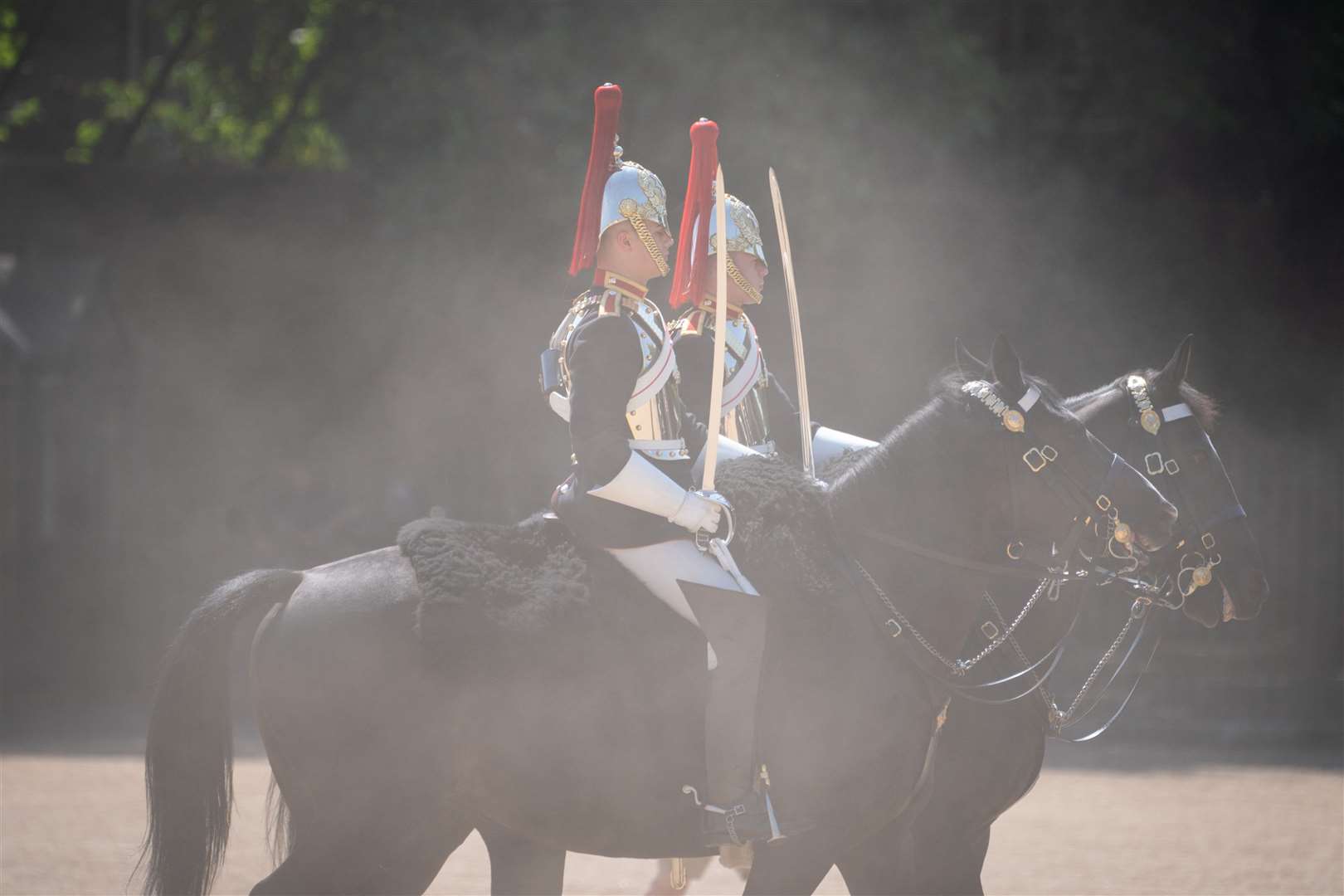Members of the Household Cavalry kick up the dust as they ride across Horse Guards Parade, London (Dominic Lipinski/PA)