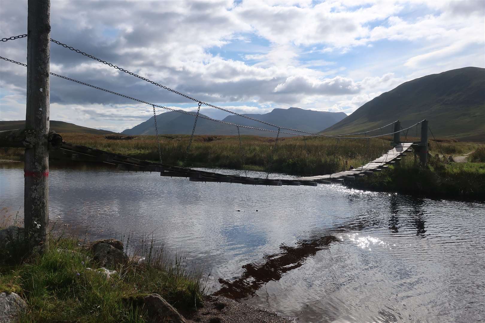 The rickety suspension bridge that crosses the Allt a' Chaoil-reidhe as it enters Loch Pattack, with Ben Alder in the distance.