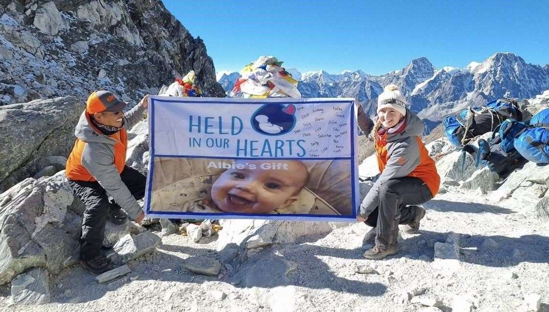 Lauren Mcfarlane from Kandoo Treks unfurls Pete MacDonald's Held in our Hearts flag at Everest base camp.