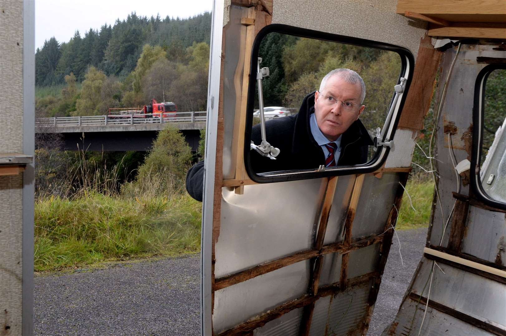 Wrecked caravan Daviot: Cllr Duncan Macpherson looking inside the abandoned caravan. A9 bridge over the River Nairn visible in background.Picture: James Mackenzie.