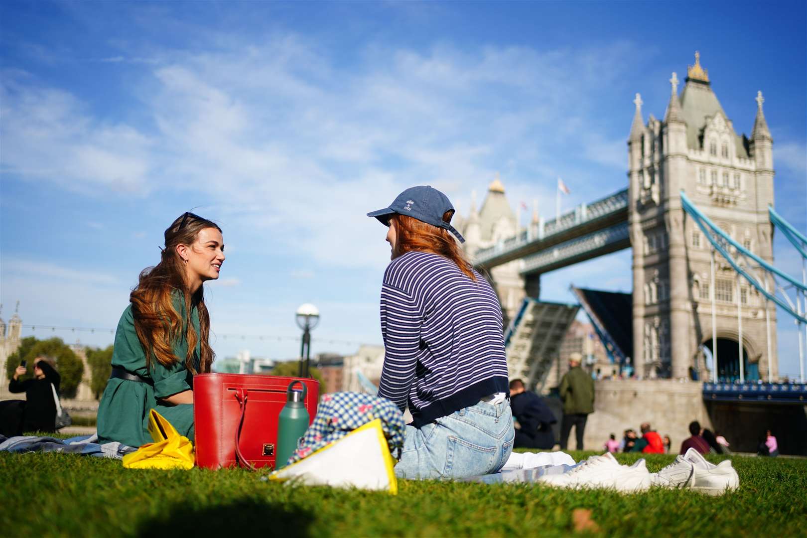 People enjoy the sunshine by Tower Bridge in London (Victoria Jones/PA)