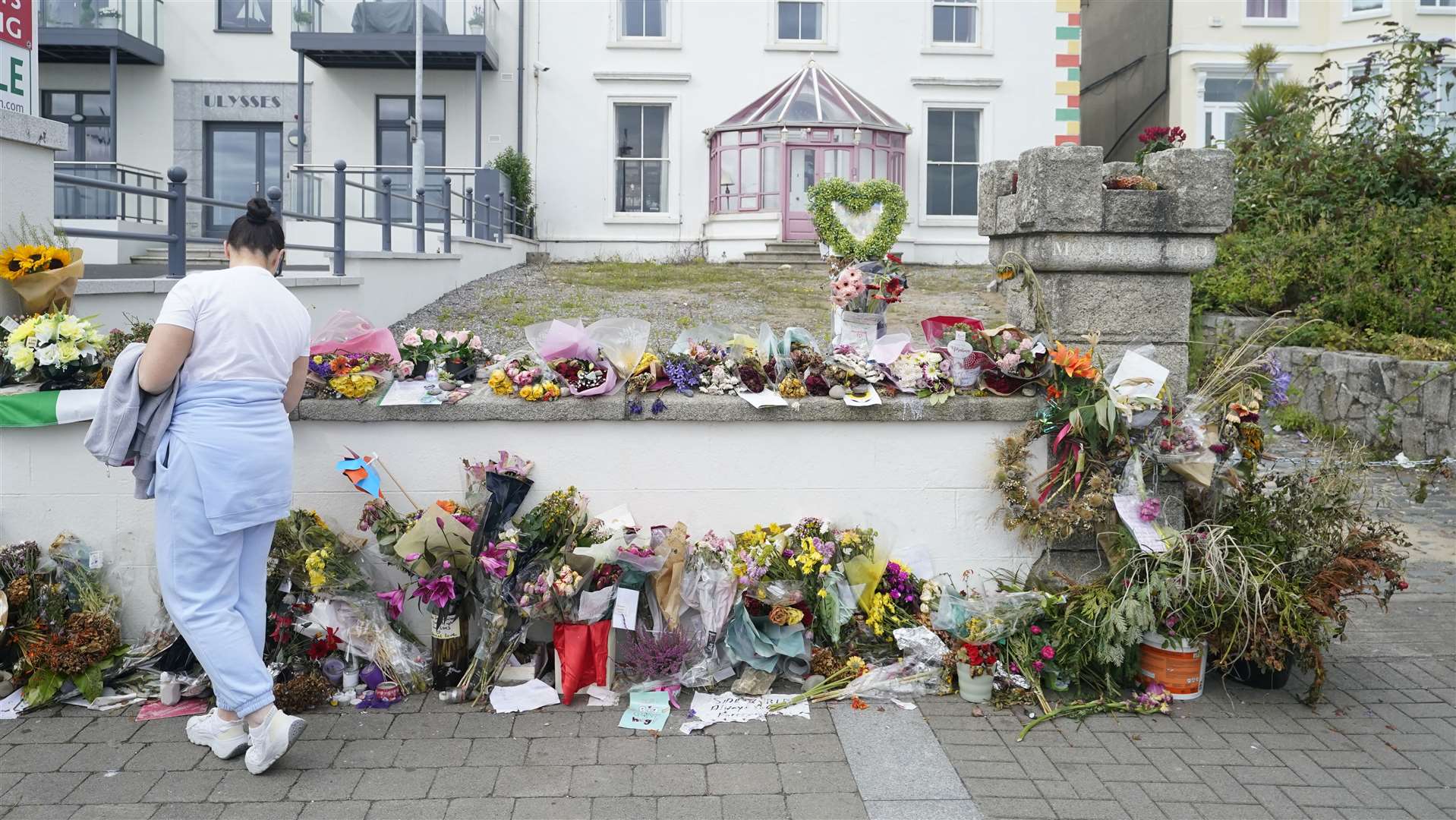 A person looking at flowers outside Sinead O’Connor’s former home in Bray (Niall Carson/PA)