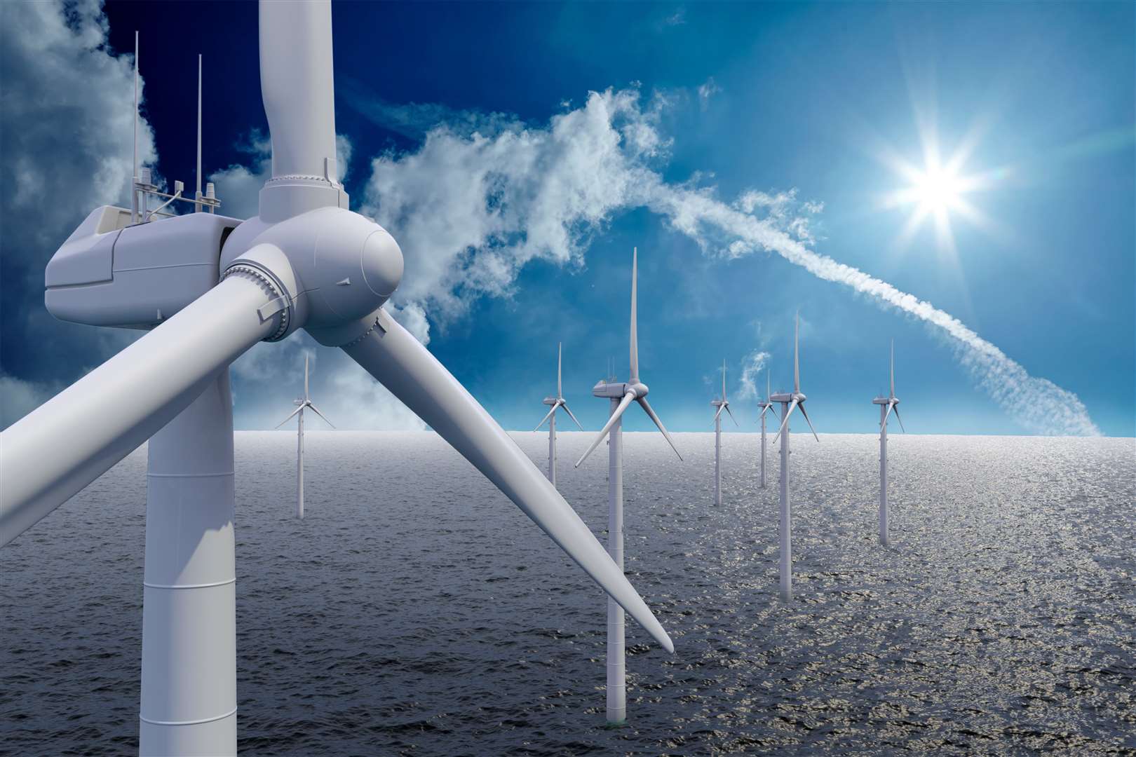 Wind power offshore with clouds and sun.